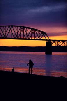 A fisherman works the shoreline between the railroad and interstate bridges at Chamberlain.